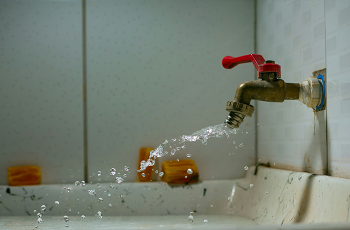 Running water splashing from a red-handled faucet over a white sink, illustrating the retired neighbor fixing the sink. Running water splashing from a red-handled faucet over a white sink, illustrating the retired neighbor fixing the sink.
