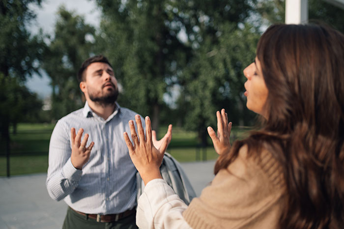 Man and woman having a heated outdoor argument, illustrating conflict related to banning children from property by entitled parent. - 9