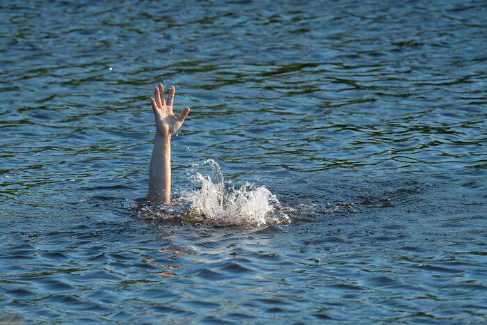A person’s hand emerging from water showing distress, illustrating unhinged family lore stories and chaos.