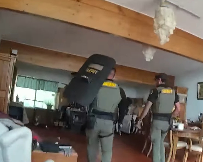 Two sheriff officers inside a home investigating the horrifying scene of a family slaying incident.