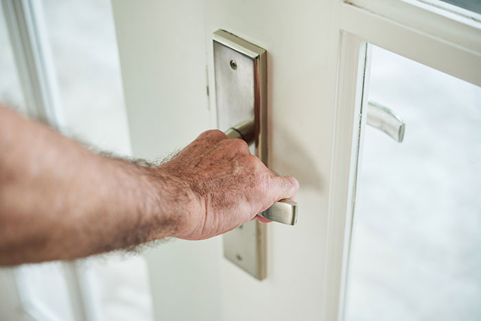 Hand gripping door handle, symbolizing father and son conflict over changing locks and house hijack dispute.