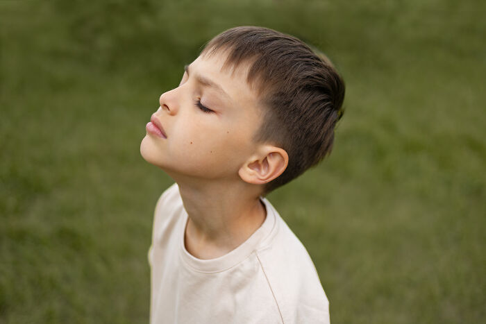 Young boy outdoors with eyes closed, reflecting on advice kids were given that was manipulation in disguise. - 9