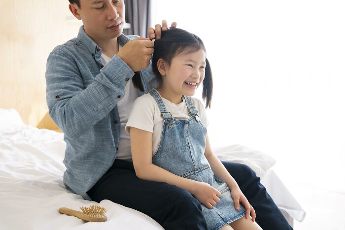 Father fixing daughter’s hair while sitting on bed, illustrating advice kids were given that later revealed manipulation. - 23