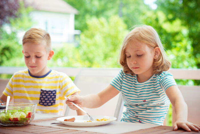 Two kids sitting at a table outdoors, having food, illustrating advice kids were given that was manipulation in disguise. - 25