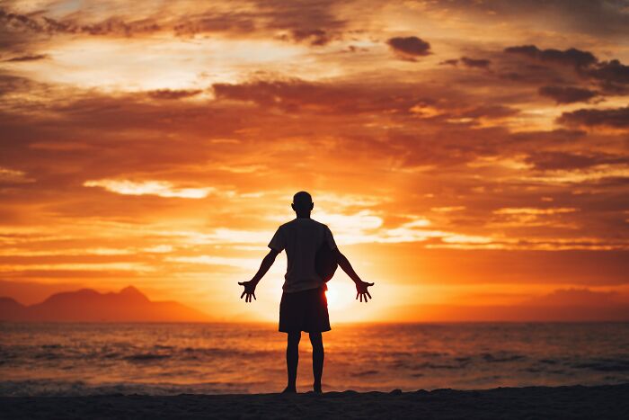 Silhouette of a person standing on the beach at sunset, symbolizing reflection on debunked lies people believe.