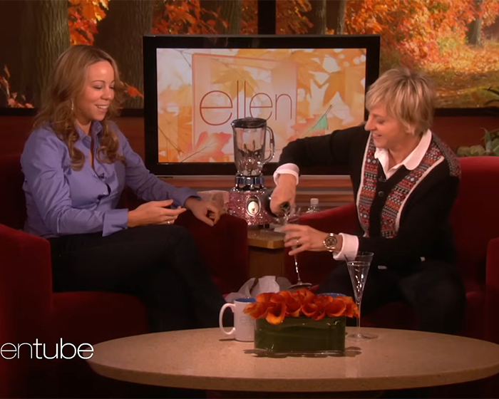 Ellen DeGeneres pouring a drink while interviewing Mariah Carey during a daytime talk show segment indoors. - 8