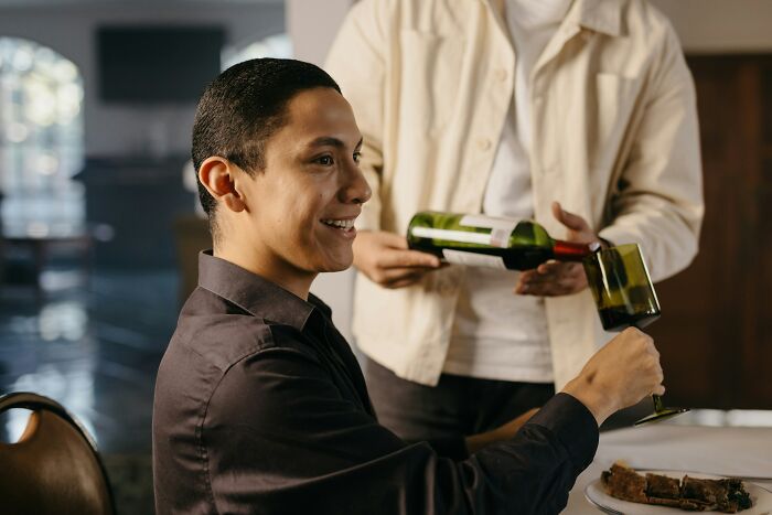 Young man smiling while pouring a drink, illustrating the theme of outrageous student names shared by a teacher.