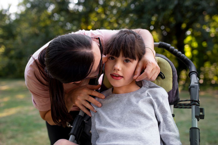Woman showing affection to her disabled stepsister in a wheelchair, highlighting family dynamics and emotional support outdoors. - 8