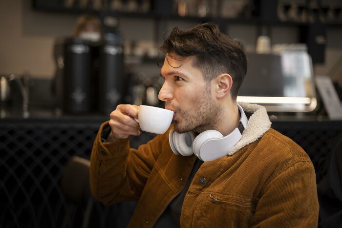 Man in a brown jacket drinking coffee at a café, reflecting on wife’s infidelity and divorce after 10 years.