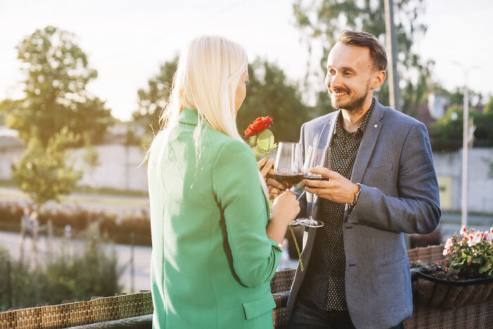 Man giving woman a red rose and wine glasses outside, illustrating themes of wife's infidelity and troubled marriages.