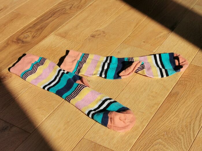 Mismatched colorful striped socks on wooden floor symbolizing relationship shenanigans and reasons people left partners.
