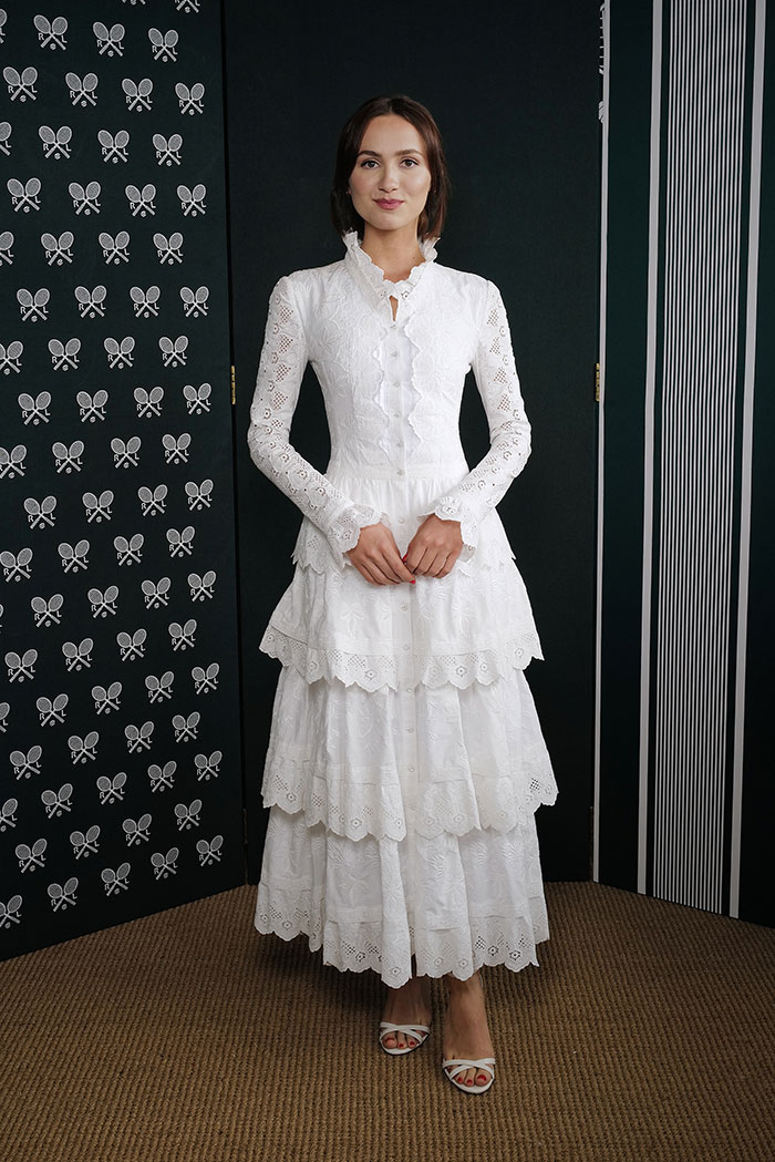 Woman in a long white lace dress posing indoors at a Wimbledon 2025 event showcasing celebrity fashion looks.