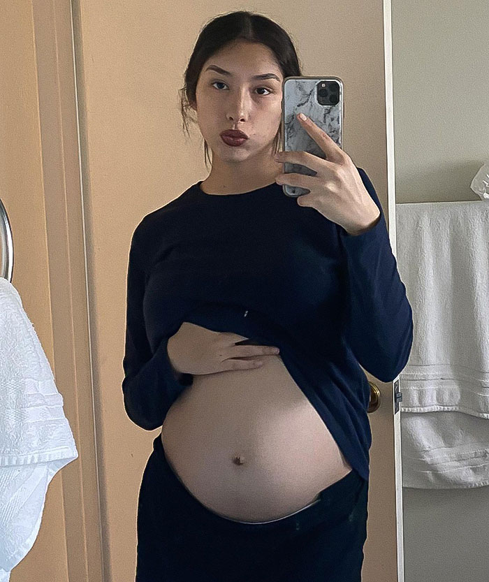 Pregnant woman taking a mirror selfie, highlighting mass outrage over baby who passed away after mom left him in the car. Pregnant woman taking a mirror selfie, highlighting mass outrage over baby who passed away after mom left him in the car.