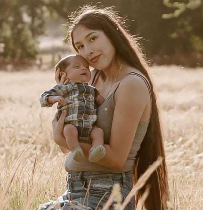 Mother holding baby outdoors in a field, related to mass outrage over baby who passed away after being left in car. Mother holding baby outdoors in a field, related to mass outrage over baby who passed away after being left in car.