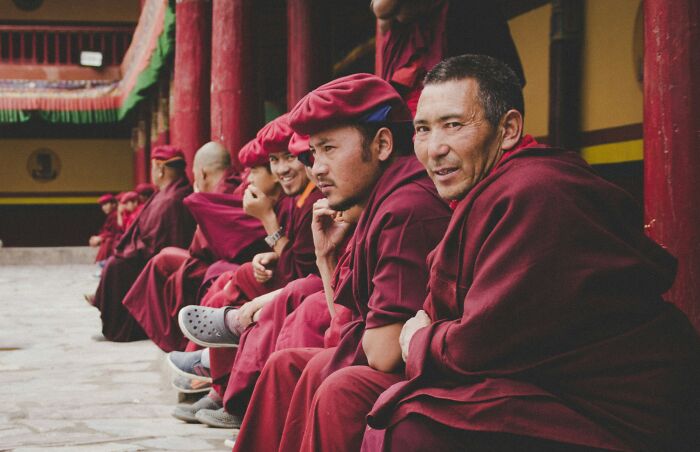 Group of monks in red robes sitting outside a temple, illustrating common religious myths about Jesus and the Bible.