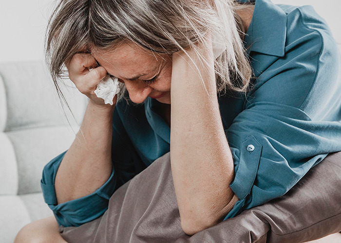 Woman holding tissue and looking distressed, illustrating the emotional impact of being gaslit by a doctor.