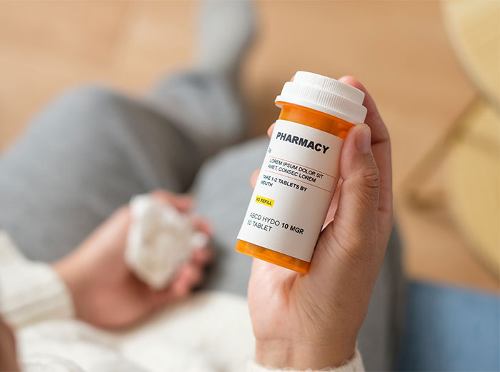 Person holding a standard U.S. pharmacy pill bottle, highlighting differences from European pharmacy packaging. Person holding a standard U.S. pharmacy pill bottle, highlighting differences from European pharmacy packaging.