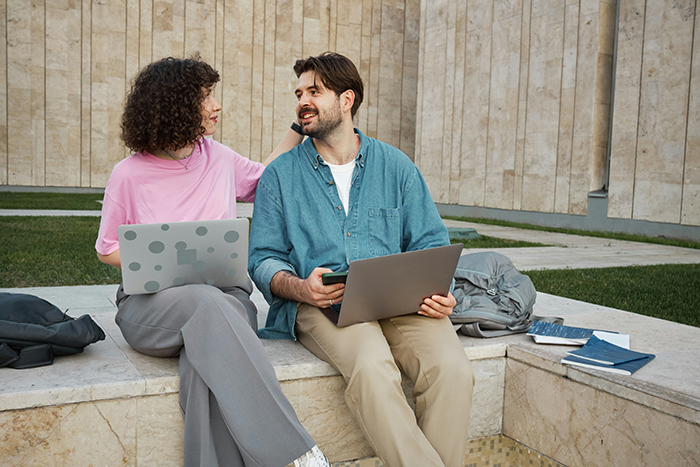 Man and woman sitting outdoors with laptops, sharing a moment of connection during his emotional healing journey. - 1