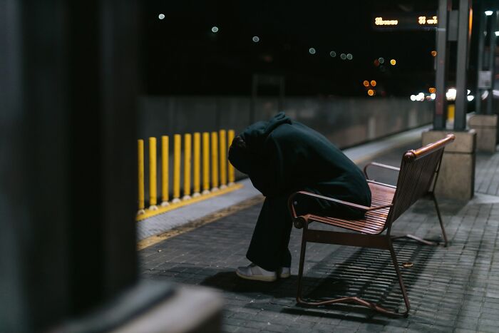 Person in dark clothes sitting alone on a bench at night, evoking emotions related to people who ran away from home. - 8