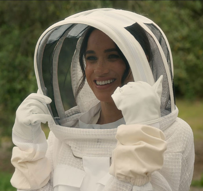 Meghan Markle wearing protective beekeeping gear outdoors, linked to embarrassing fruit-picking photo accusations.