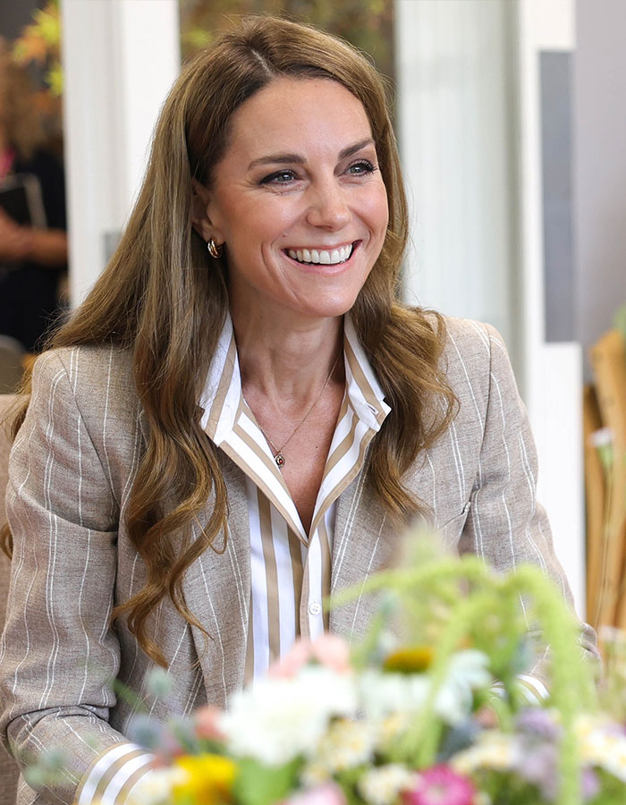 Kate Middleton’s ex-assistant smiling during a public engagement, wearing a striped shirt and light blazer. - 6