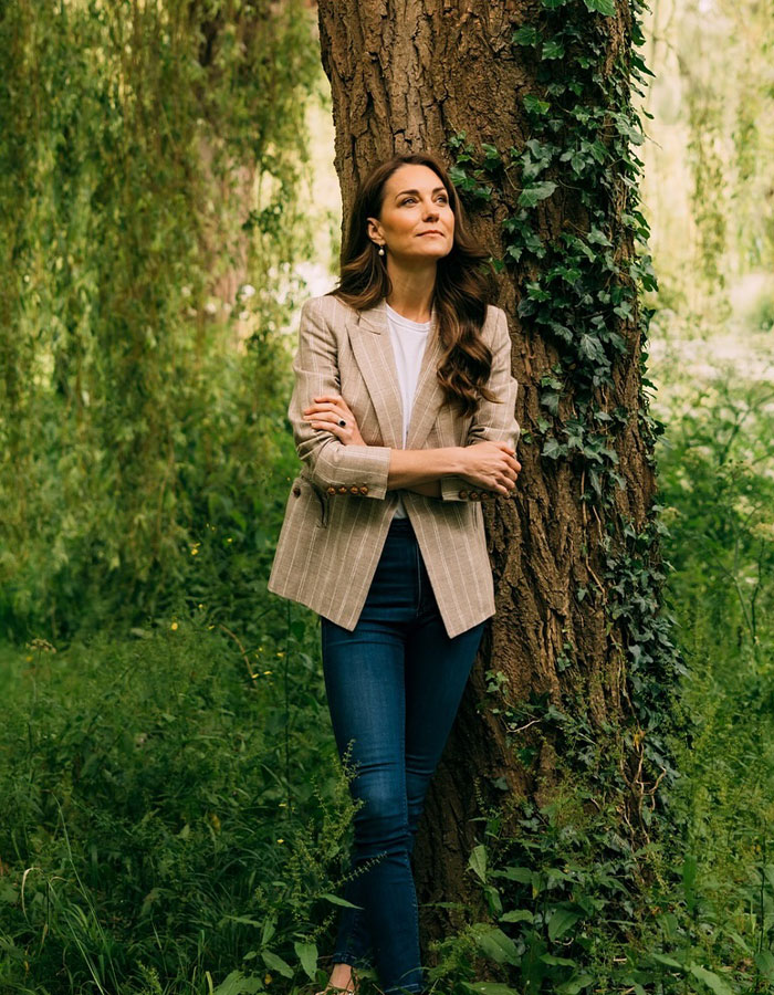 Kate Middleton’s ex-assistant standing by tree in casual blazer and jeans, looking thoughtful in a green outdoor setting. - 7