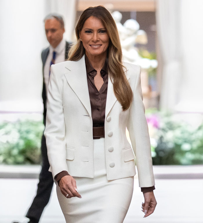 Melania Trump wearing white suit highlighting her curves while walking confidently in a formal setting Melania Trump wearing white suit highlighting her curves while walking confidently in a formal setting