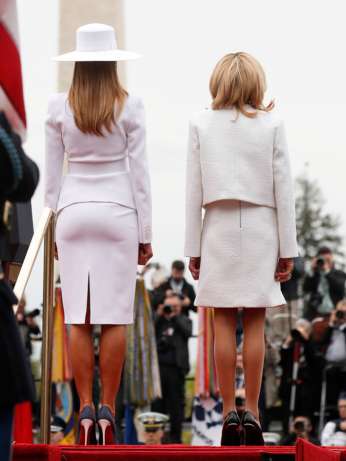 Melania Trump and Brigitte Macron standing side by side, showcasing Melania Trump’s curves in elegant white outfits. Melania Trump and Brigitte Macron standing side by side, showcasing Melania Trump’s curves in elegant white outfits.