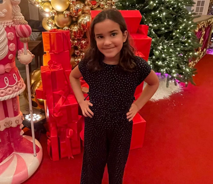 Young girl standing with hands on hips near decorated Christmas tree and wrapped presents, police noting inconsistencies in report - 11
