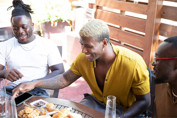 Three men sitting on a patio enjoying snacks and drinks while sharing stories that drive wives crazy.