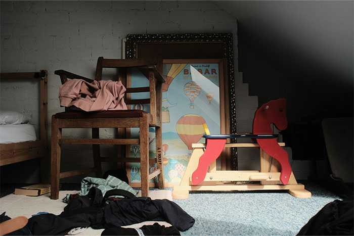 Cluttered room with wooden chair, children's rocking horse, and scattered clothes symbolizing things that drive my wife crazy.