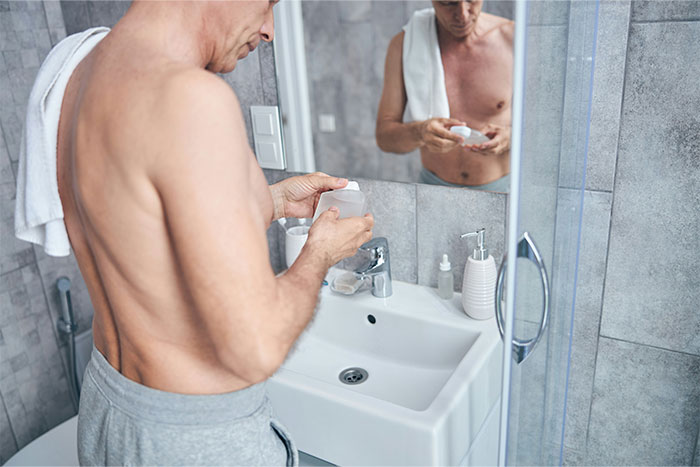 Man in bathroom holding a container, illustrating challenges men face explaining things that drive their wife crazy.
