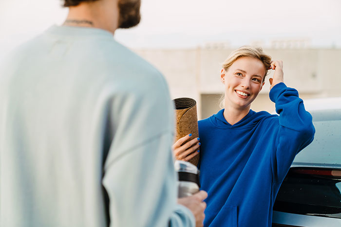 A smiling woman in a blue hoodie talking to a man, illustrating things men shouldn’t do while pursuing women. - 30