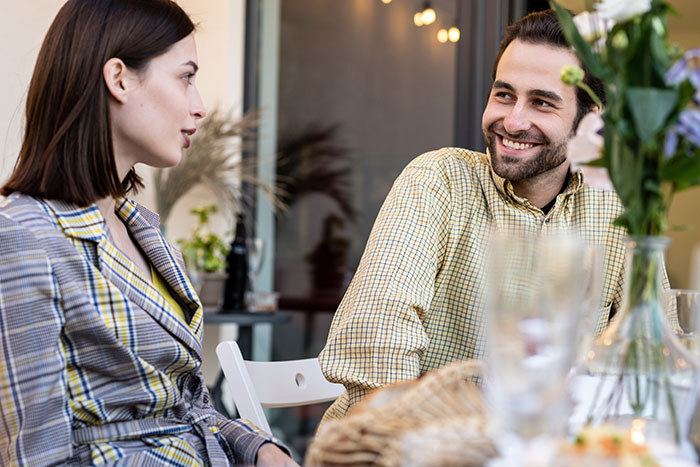 Man and woman having a conversation in a casual setting, illustrating things men shouldn’t do while pursuing women. - 10