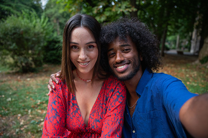 Couple taking a selfie outdoors, highlighting things men shouldn’t do while pursuing women in dating advice. - 21