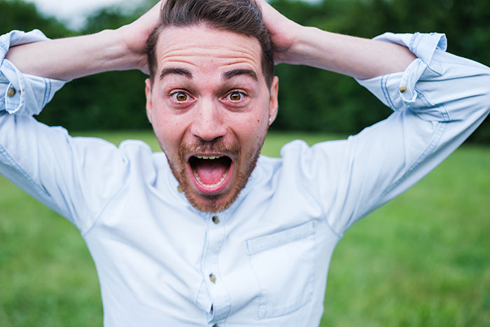 A surprised man outdoors with hands behind head, reacting to common mistakes men make while pursuing women. - 3