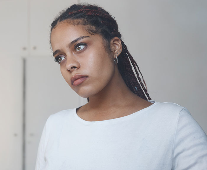 Young woman with braided hair wearing a white shirt, looking thoughtful about things men shouldn’t do while pursuing women. - 27