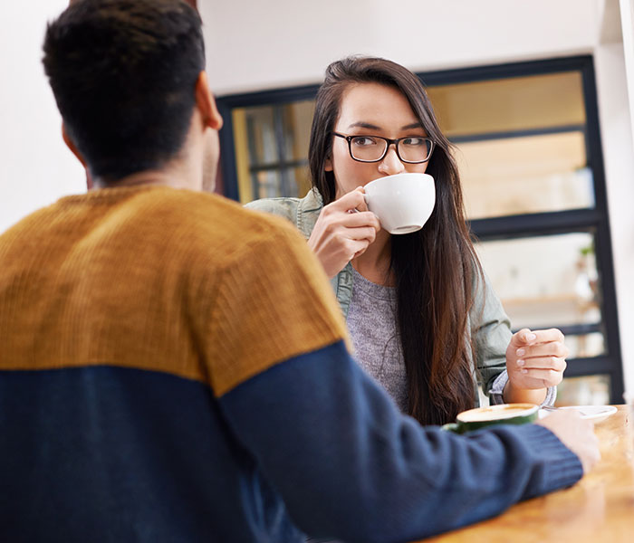 Man and woman having coffee at a cafe, illustrating things men shouldn’t do while pursuing women advice online. - 16