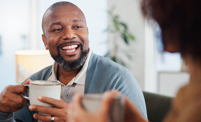 Man smiling while holding a coffee cup during a casual conversation, illustrating things men shouldn’t do pursuing women - 23