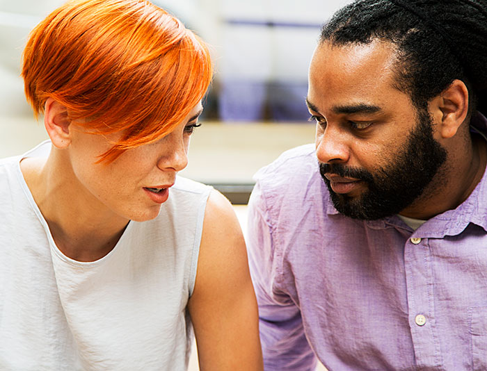 Woman with short red hair talking to bearded man with dreadlocks wearing a purple shirt, illustrating things men shouldn’t do while pursuing women. - 18