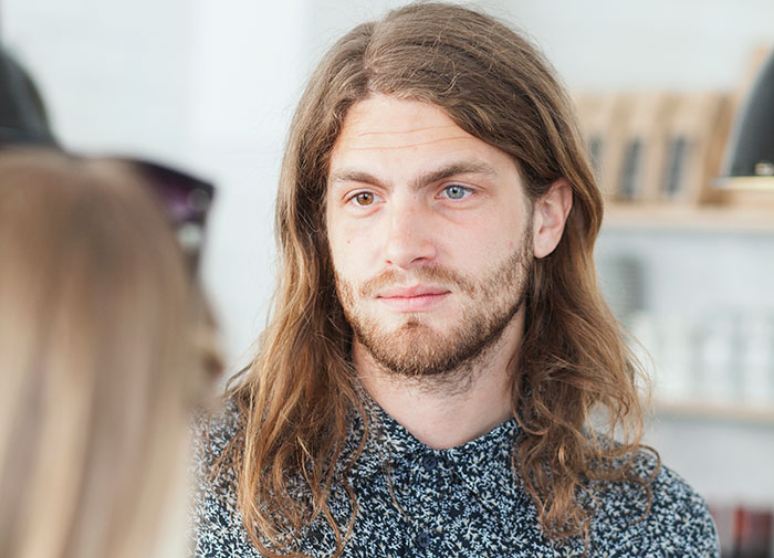 Man with long hair and beard listening attentively while pursuing women in a casual indoor setting - 8