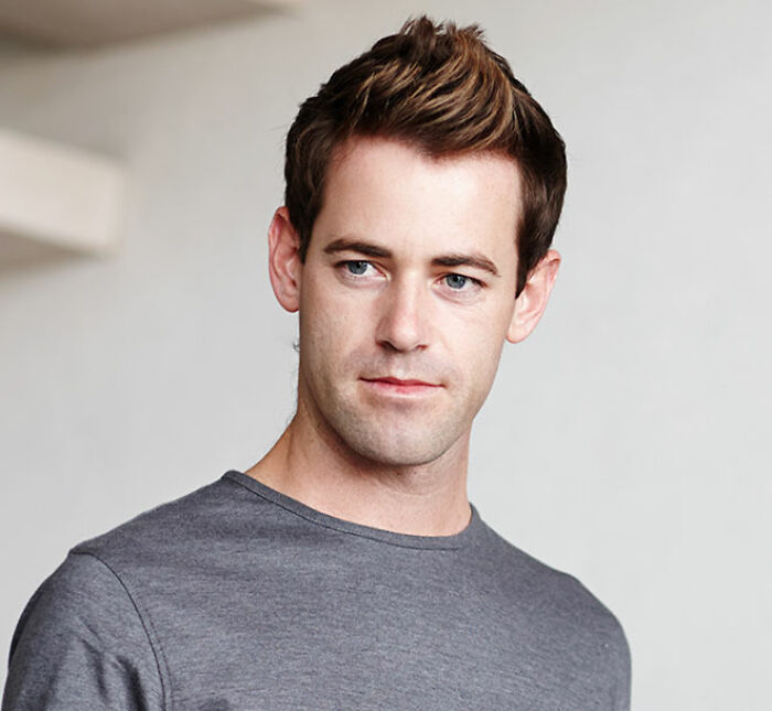 Young man in a gray shirt looking away thoughtfully, illustrating things men shouldn’t do while pursuing women. - 35