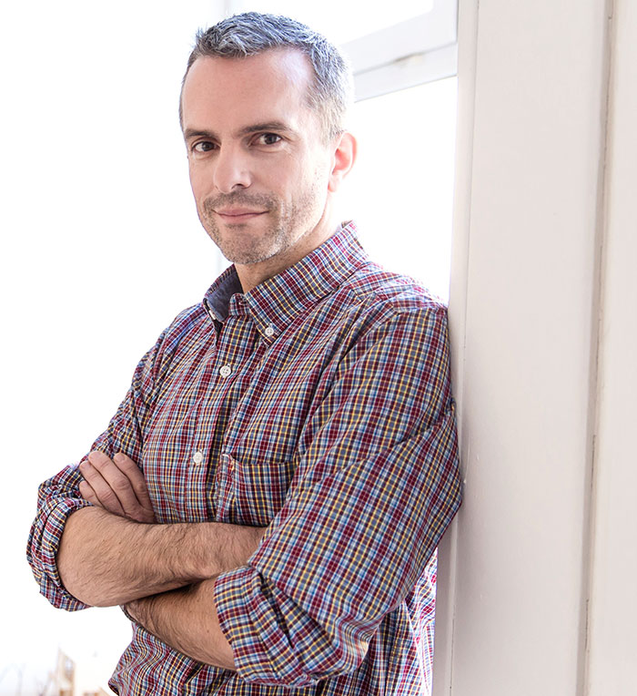 Man leaning against a wall with arms crossed, representing things men shouldn’t do while pursuing women advice. - 4