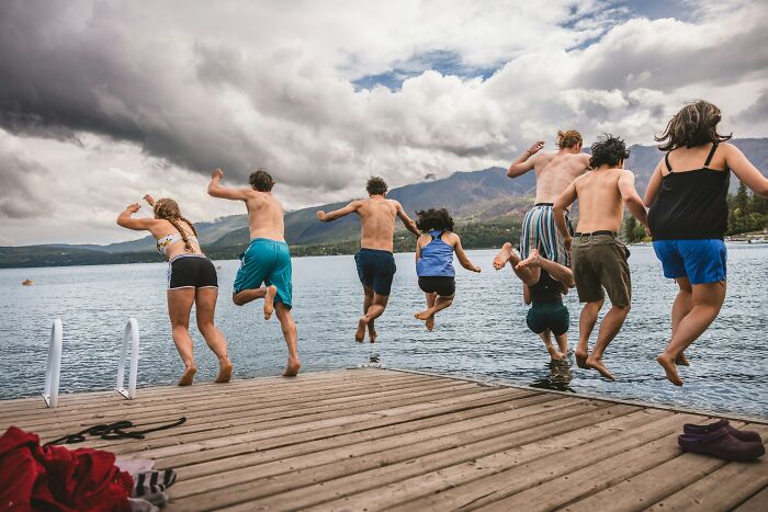 Group of people jumping off a dock into a lake, capturing a moment of a gut feeling that led to a life-saving experience.