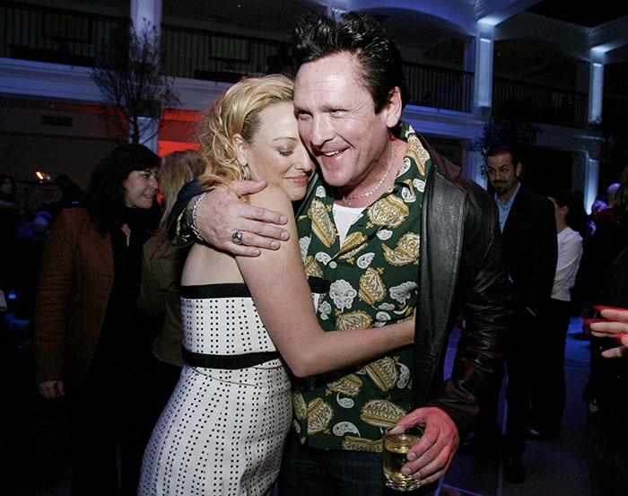 Actor Michael Madsen warmly hugging a woman at an indoor event, capturing a heartfelt moment of connection.