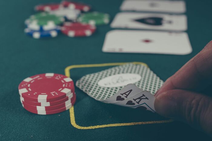 Close-up of a hand revealing winning poker cards near stacked chips on a green casino table during intense gameplay.
