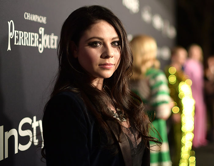 Woman with long dark hair posing at a celebrity event, highlighting stars we've lost this year in July.