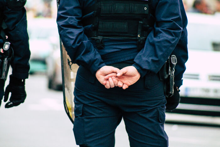 Two officers in dark uniforms with tactical gear standing on a city street, related to people who deal with dead bodies.