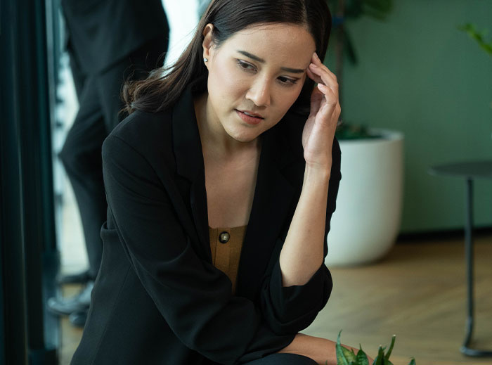 Worried woman sitting indoors, reflecting on family drama involving entitled grandma and grandson&rsquo;s ashes dispute.