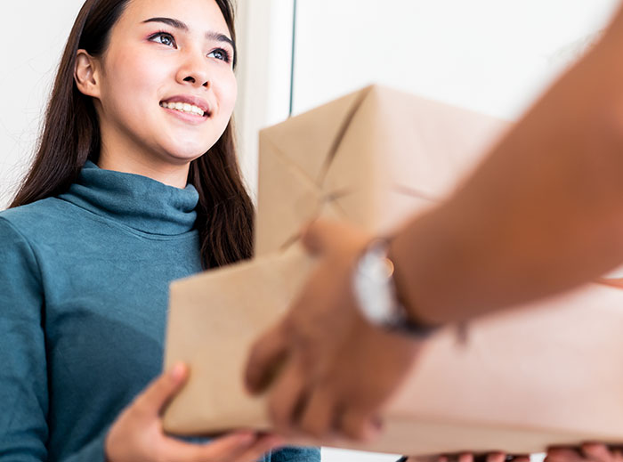 Young woman receiving a package indoors, illustrating family drama involving entitled grandma and grandson&rsquo;s ashes conflict.